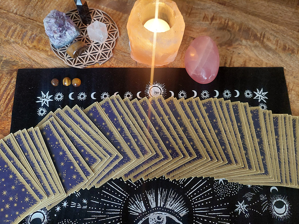 Jeu de cartes oracle et tarot posé sur une table rituelle, ambiance spirituelle et lumineuse.